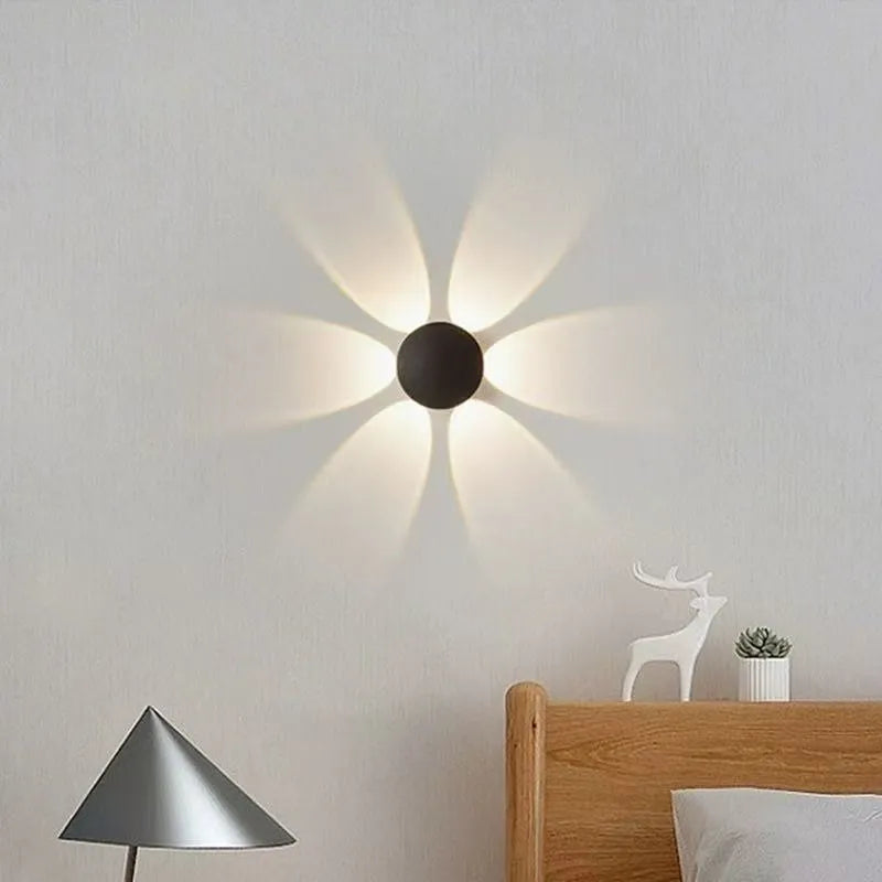 A wireless black floral motion sensor wall lamp casting a beautiful petal-shaped warm light above a wooden bed headboard.