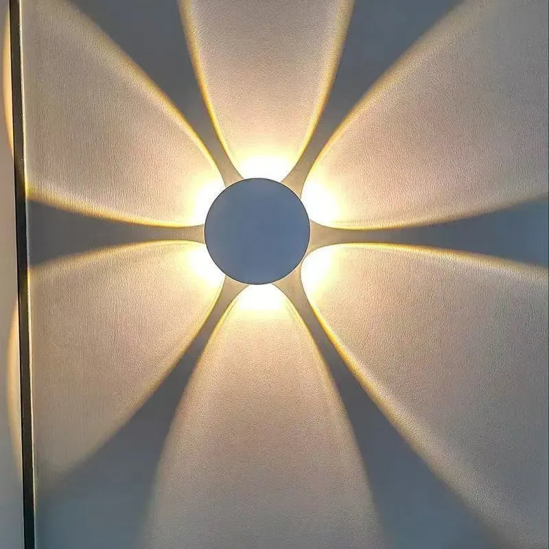 Close-up of a 6-way modern LED wall light projecting a warm yellow floral pattern on a wall.