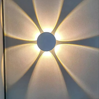 Close-up of a 6-way modern LED wall light projecting a warm yellow floral pattern on a wall.