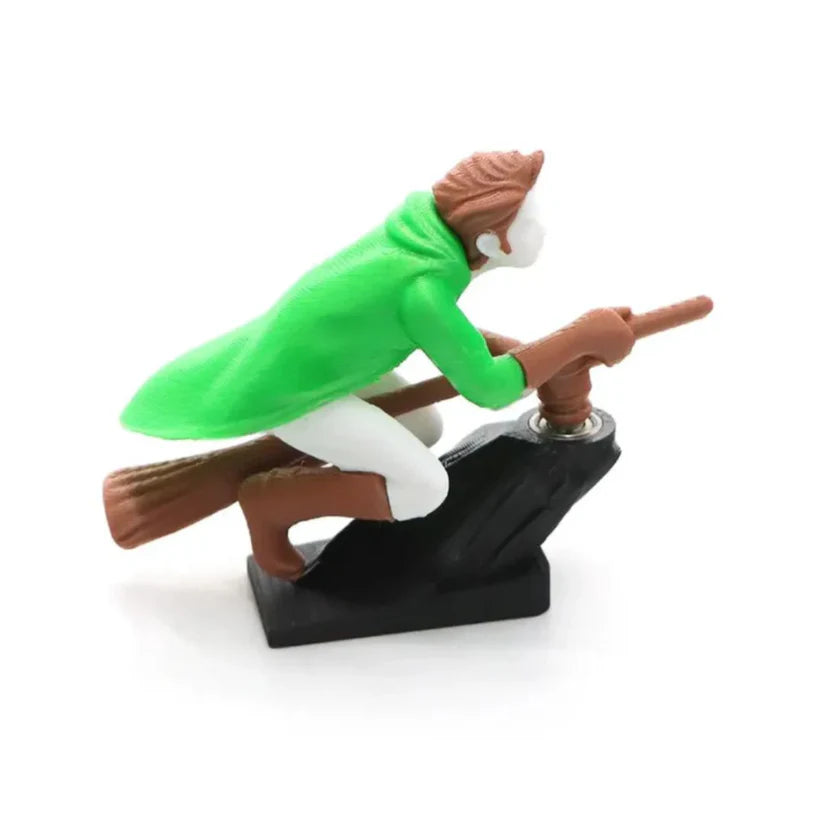 A green-hooded wizard riding a flying broomstick, featured as a motion-activated car interior drift ornament.