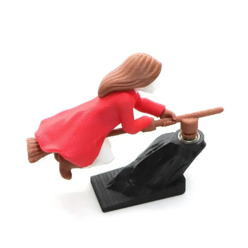 Rear-side view of a 3D-printed red witch riding a broomstick dashboard drift ornament with a black base.