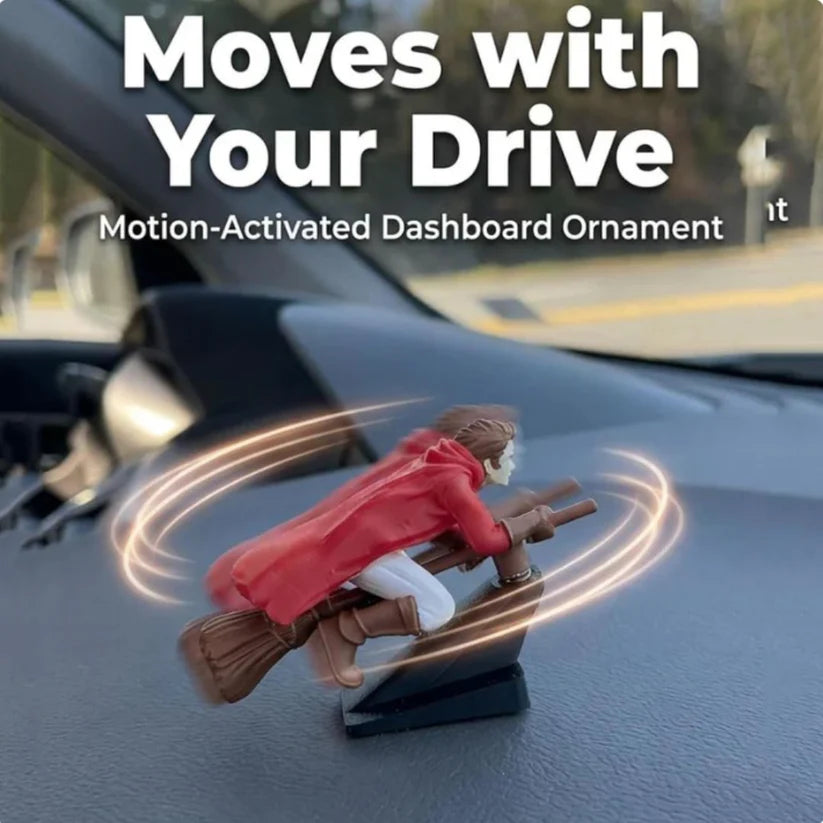 A red wizard flying broomstick ornament drifting on a car dashboard, illustrating the motion-activated movement while driving.
