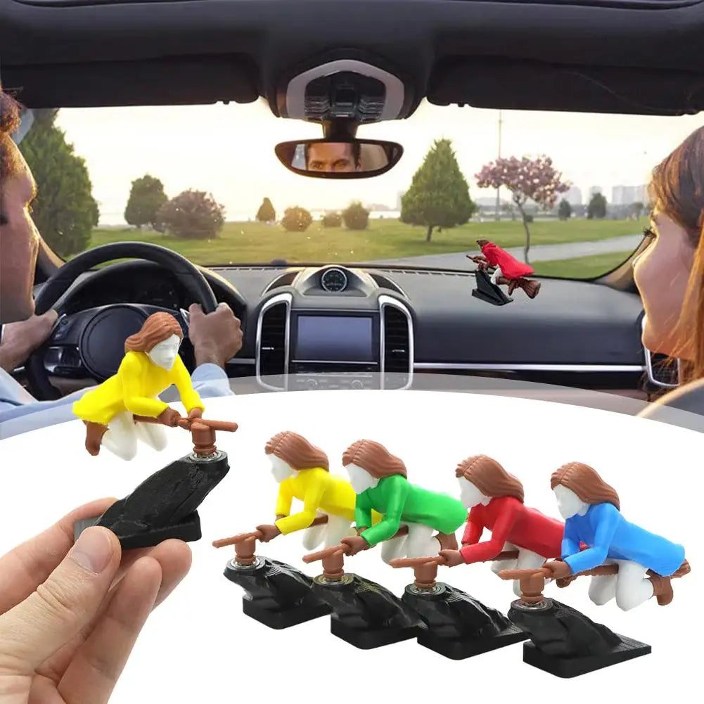 Four colorful witch dashboard ornaments lined up in a row on a car dashboard, with a street view through the windshield.