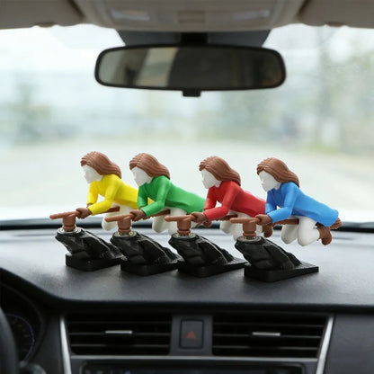 Four colorful witch dashboard ornaments lined up in a row on a car dashboard, with a street view through the windshield.